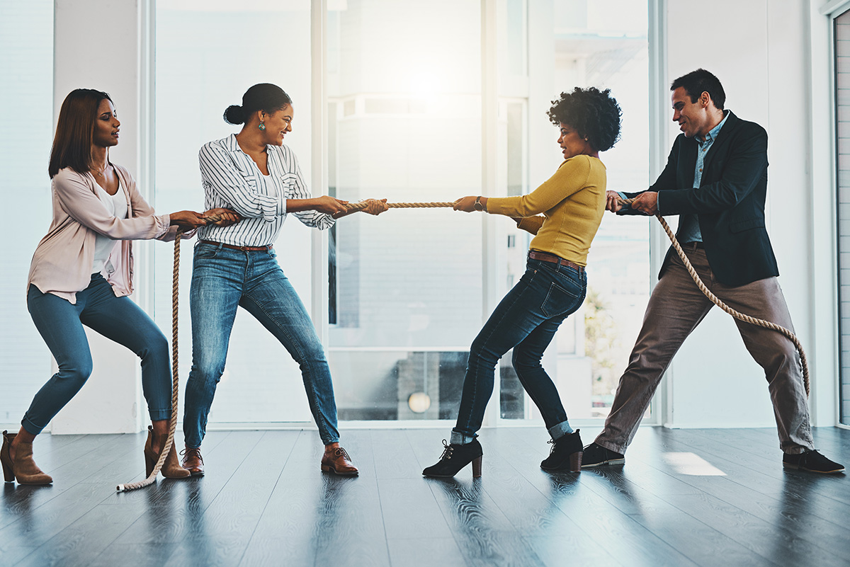 Shot of a group of businesspeople pulling on a rope during tug of war in an office